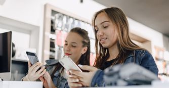 Dos usuarias comparando celulares en una tienda de tecnología.